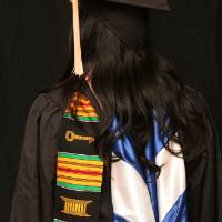 woman shows off her cap and gown for a picture